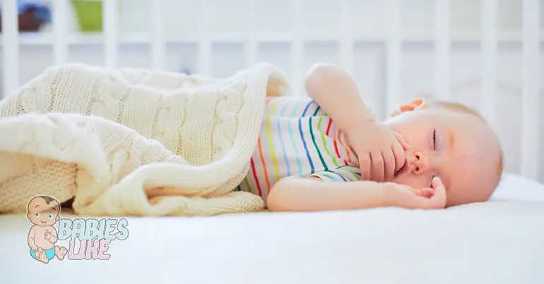 Baby asleep in a mini crib lying on a comfortable mattress